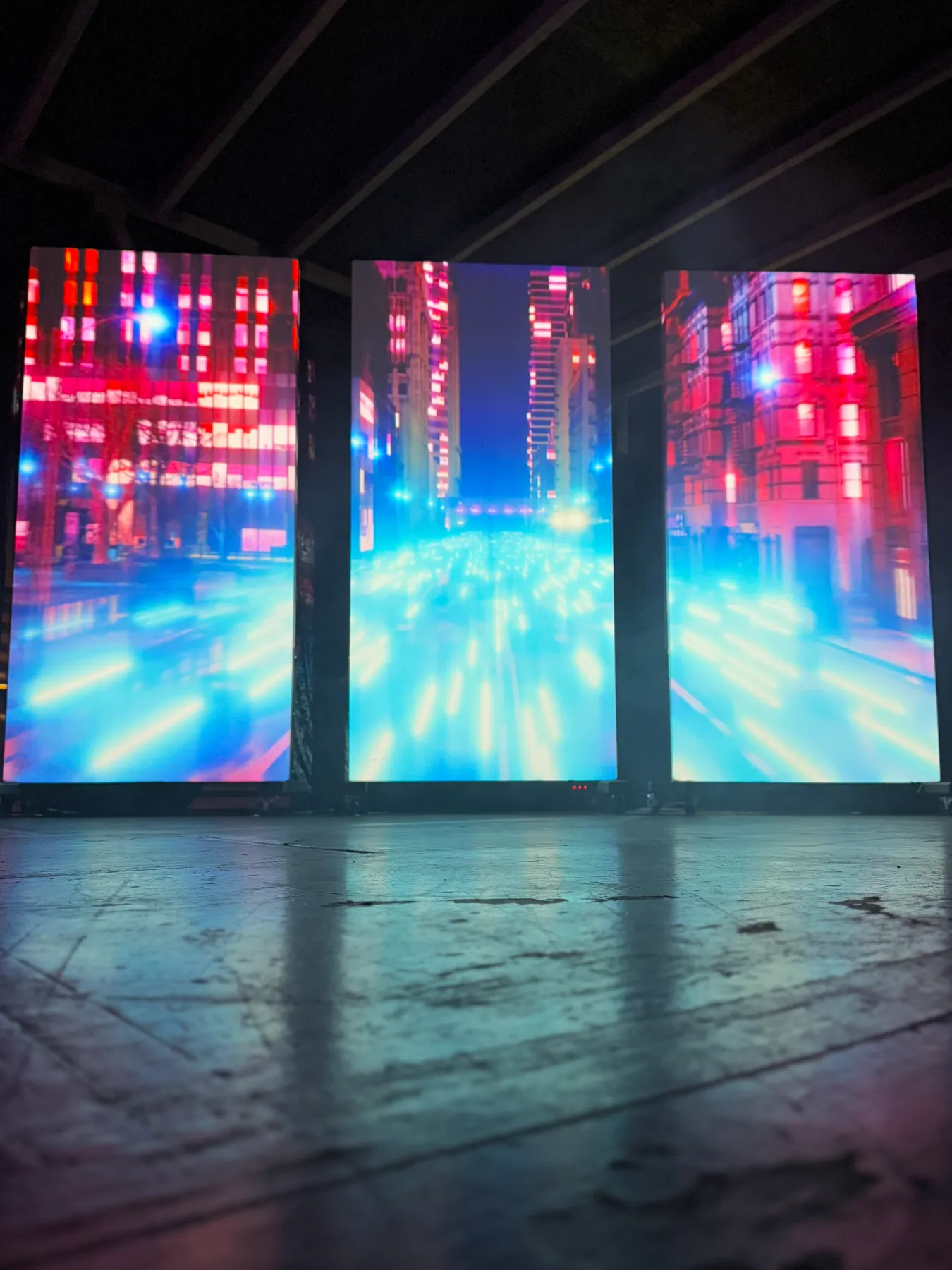 Three 8-foot projection panels showing neon city streets in red and blue light, Nocturnal installation, San Diego