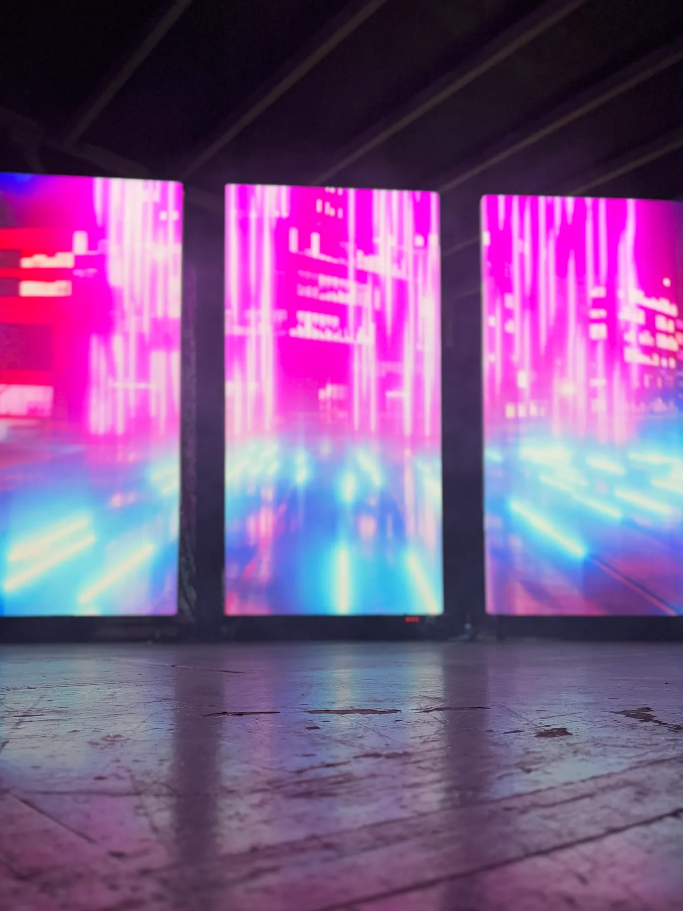 Magenta and blue light-streak cityscape projected across three panels, Nocturnal installation