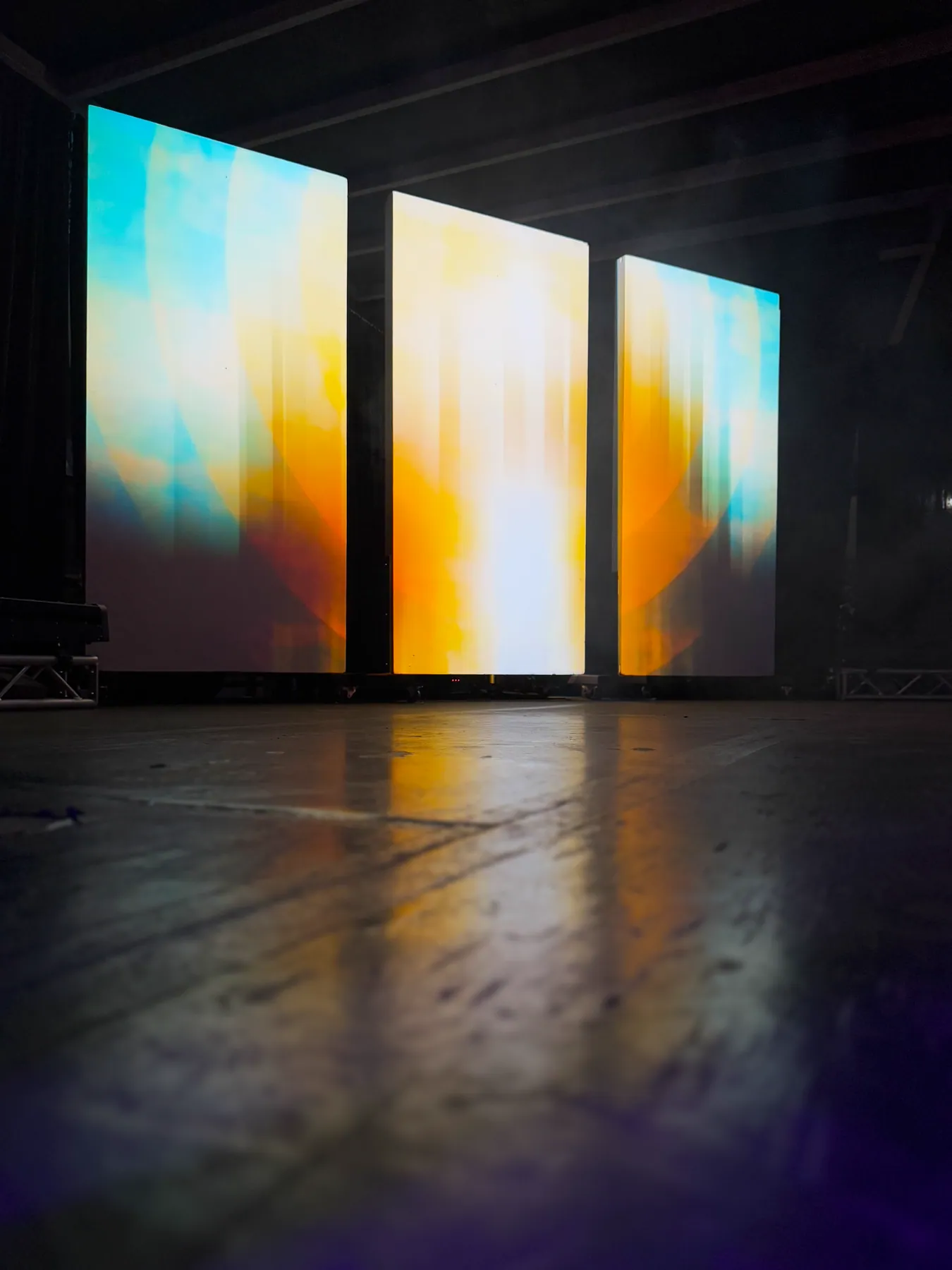 Three panels glowing with blurred dawn light in blue, white and gold, Nocturnal installation