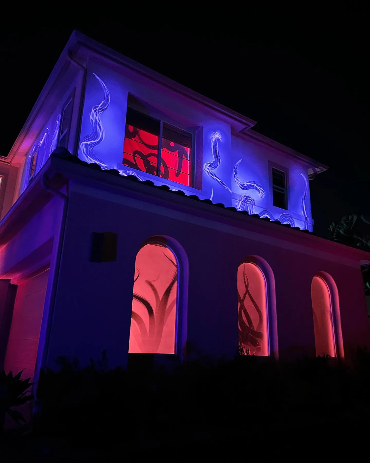 Purple tentacles projected across a two-story house facade with red-lit windows, Halloween 2021