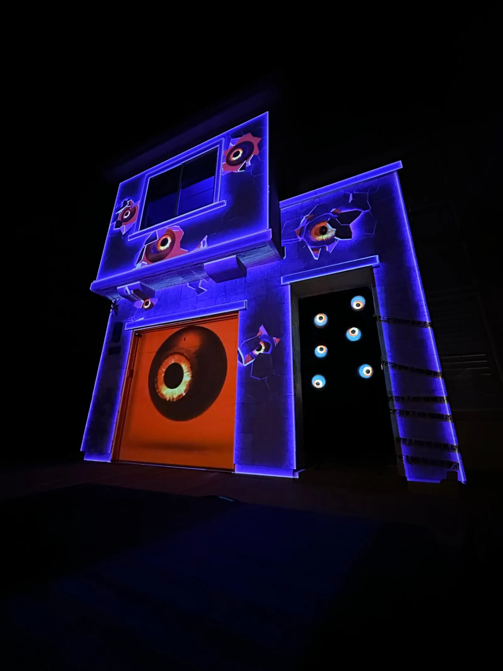 Angled view of a house mapped with a giant eye on the garage door and cracked walls, Halloween 2022