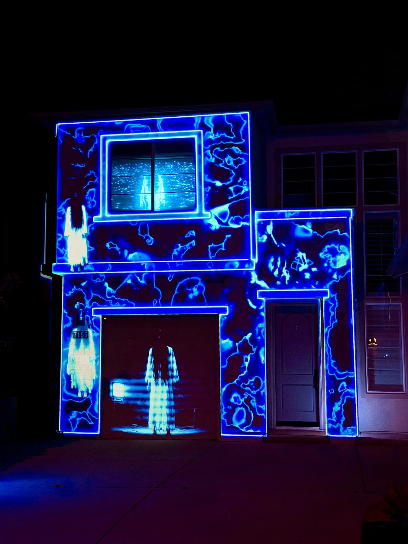 Glowing spectral figure projected on a garage door amid blue static patterns, Halloween 2025