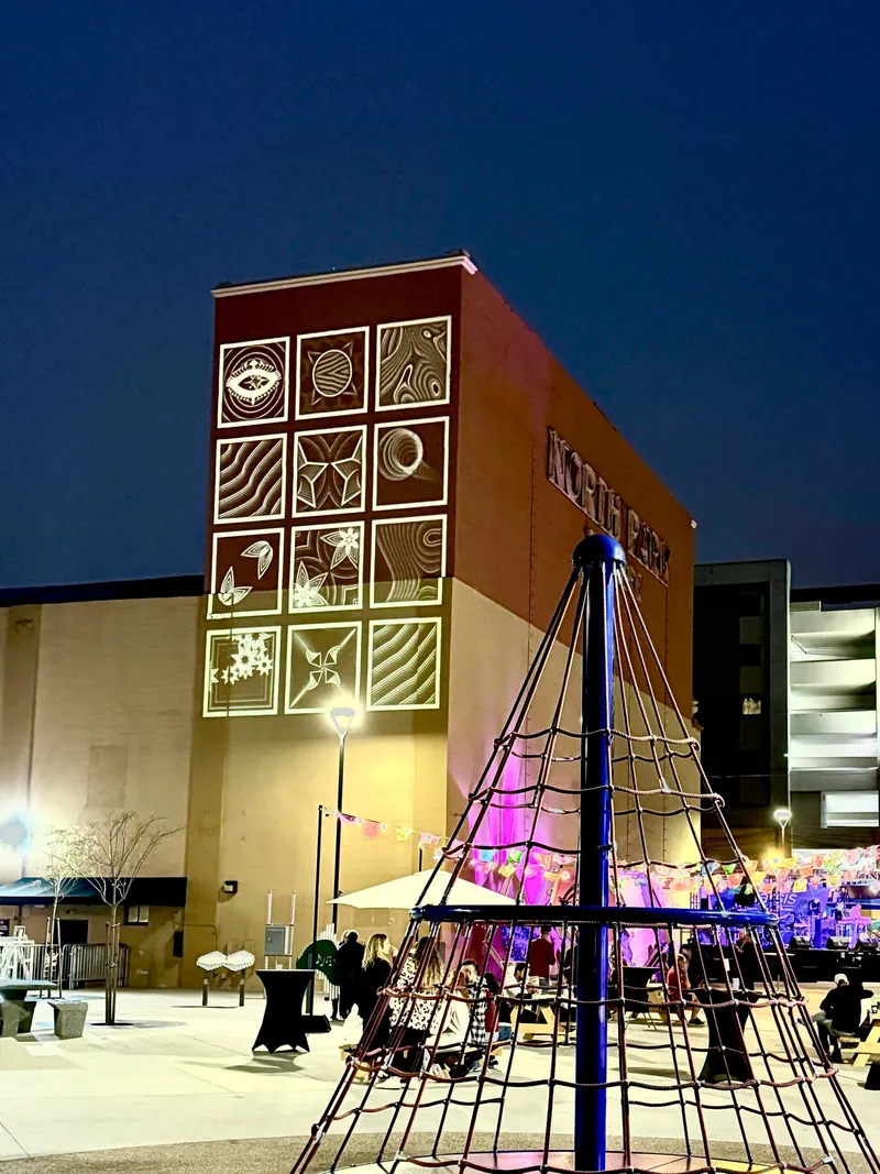 Black-and-white tiled mural projected on a tall building facade above a festival plaza, North Park Music Festival